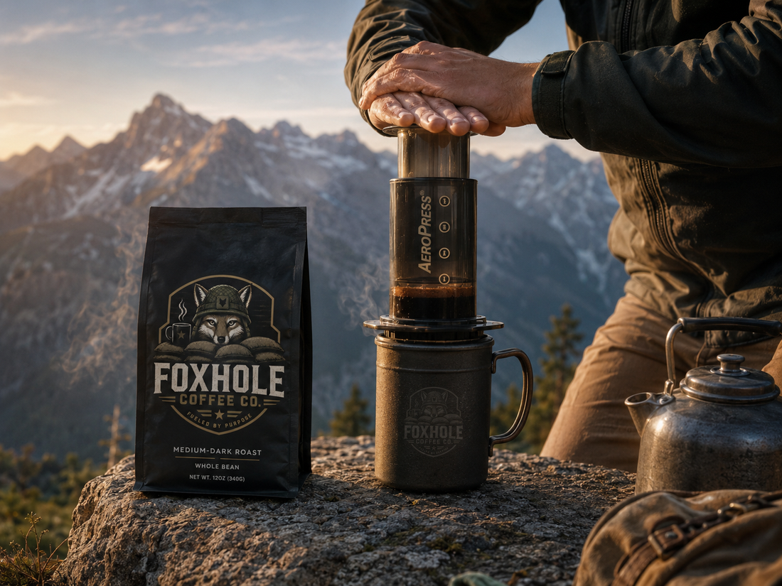 Hands pressing an Aeropress over a Foxhole Coffee mug on a mountain summit