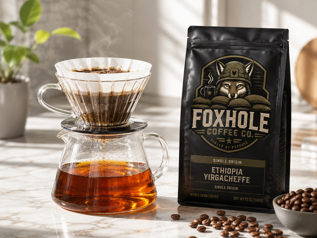Foxhole Coffee Ethiopia Yirgacheffe bag beside a glass pour-over dripper and carafe with bright amber coffee on a marble surface