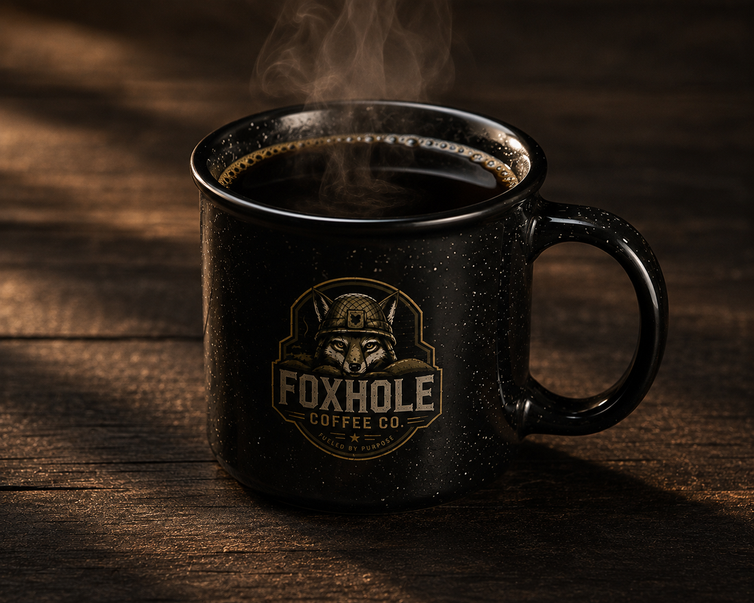 Foxhole Coffee Co. branded black camp mug with steaming black coffee on a dark wood surface